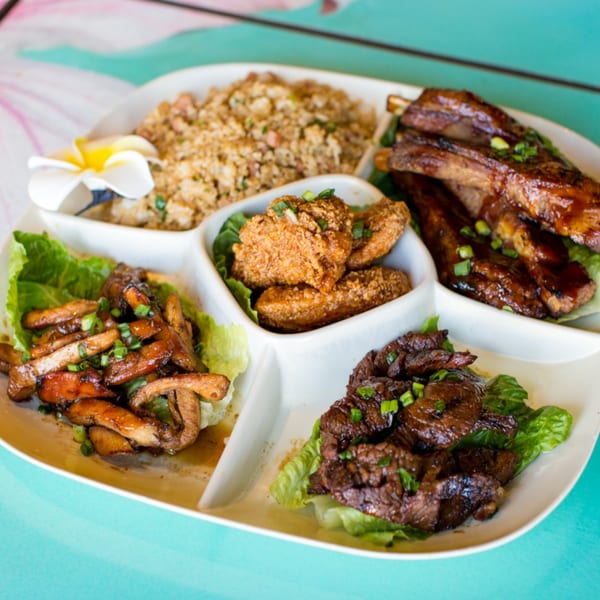 A white platter with sections of fried rice, ribs, fried chicken, and stir-fried meat.