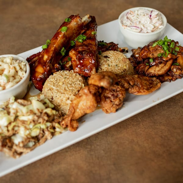 A platter of Hula Pizzeria & Grill's ribs, chicken, rice, and coleslaw.