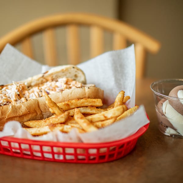 A Hula Pizzeria & Grill sandwich and fries in a red basket, with a cup of ice cream.