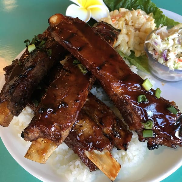 Hula Pizzeria & Grill's glazed ribs with rice, macaroni salad, coleslaw, and a plumeria.